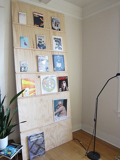 a room with a lamp, bookshelf and pictures on the wall