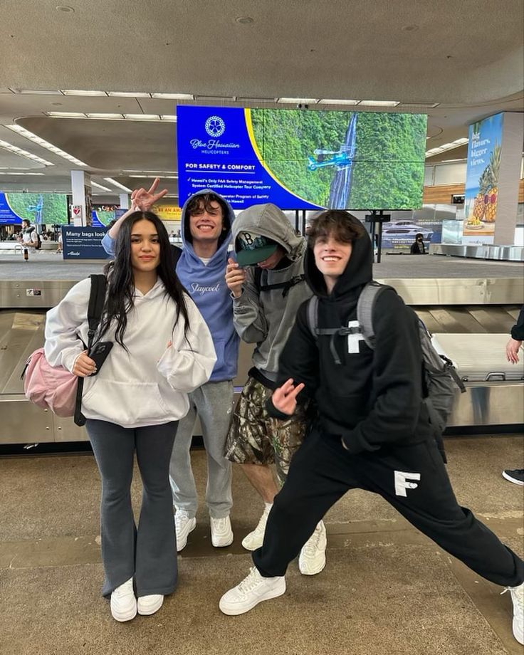 four people posing for a photo in an airport