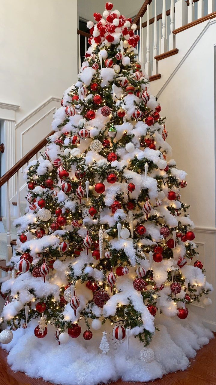 a decorated christmas tree with red and white ornaments on it in front of a staircase