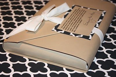 an open book with a white ribbon tied around it on a black and white patterned tablecloth