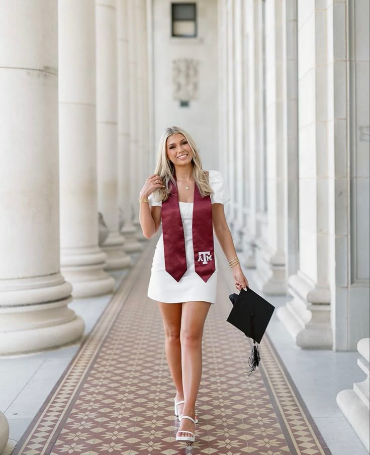 a woman in white dress and maroon scarf walking down the hallway with her hand on her hip