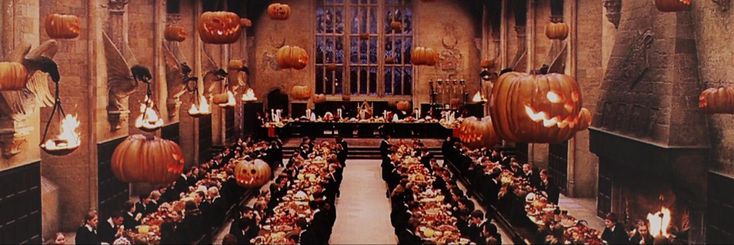 a large hall filled with lots of tables covered in pumpkins and lit up by candles