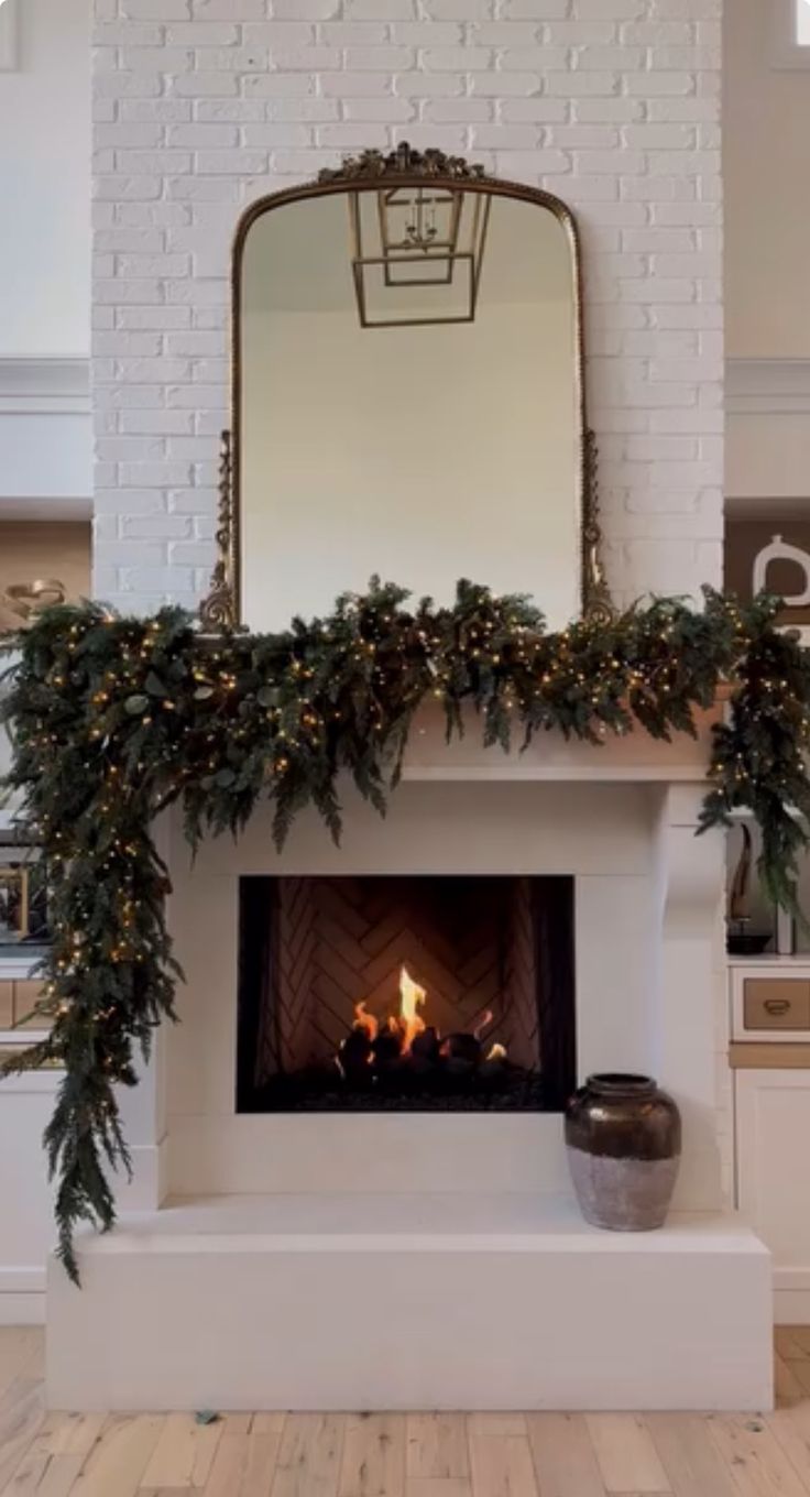 the fireplace is decorated with greenery and lights