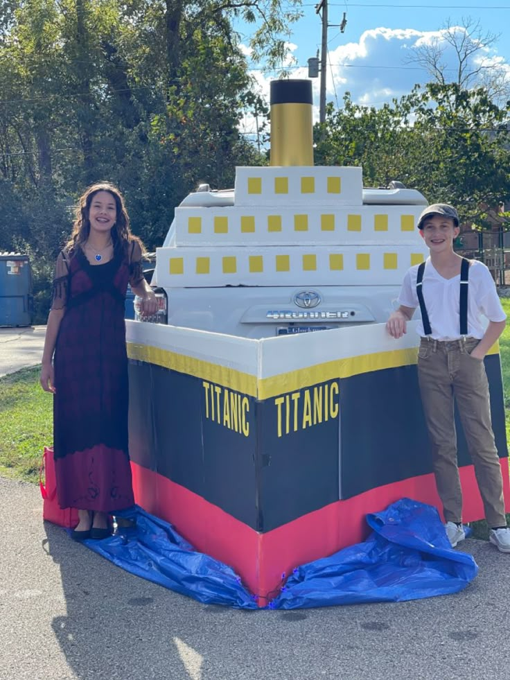 two people standing in front of a large boat shaped like a boat with the word titanic painted on it