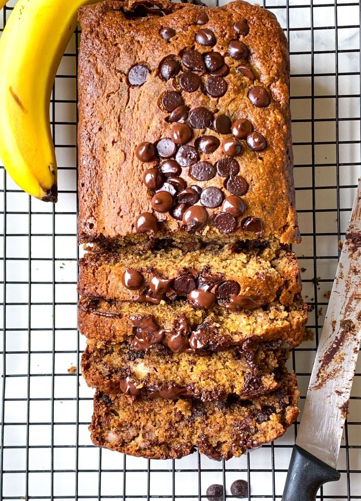 a loaf of peanut butter banana bread on a cooling rack with bananas and chocolate chips