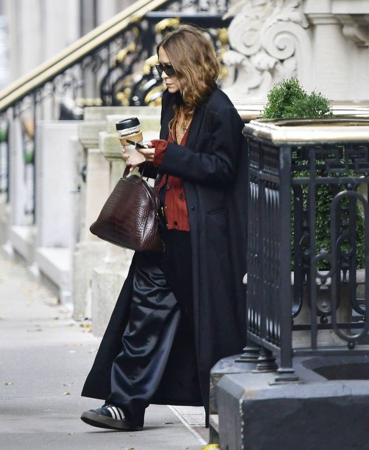 a woman is walking down the street with her purse and cell phone in her hand