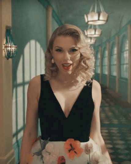 a woman with blonde hair wearing a black and white dress standing next to a hallway