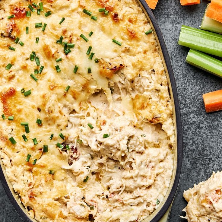 a casserole dish with chicken and carrots next to celery sticks