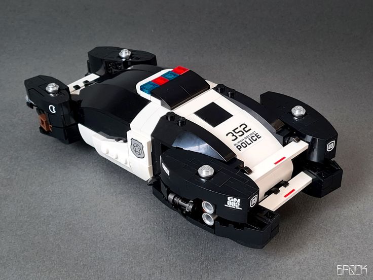 a police car made out of legos sitting on a table next to a black and white wall