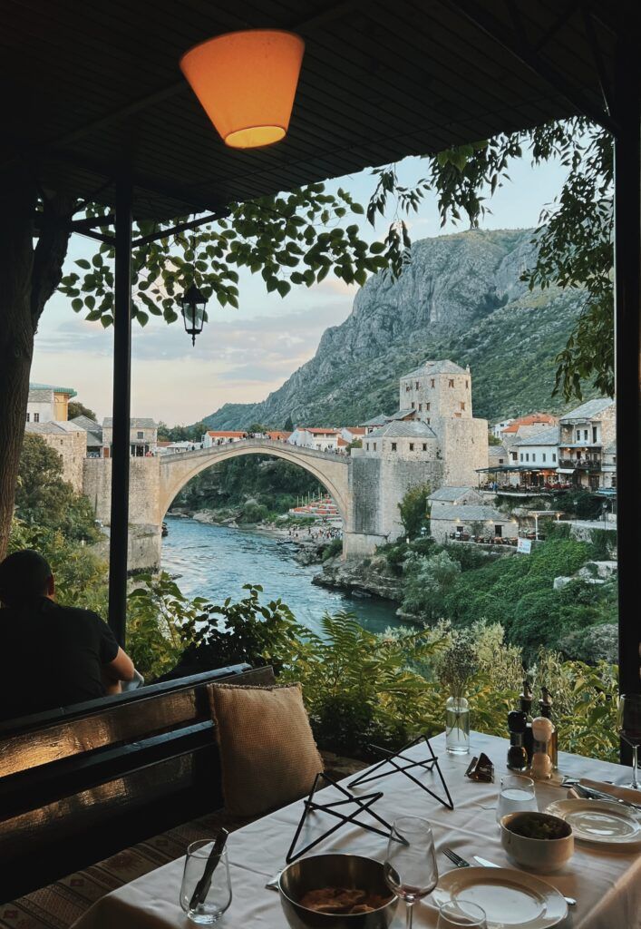 a person sitting at a table overlooking a river