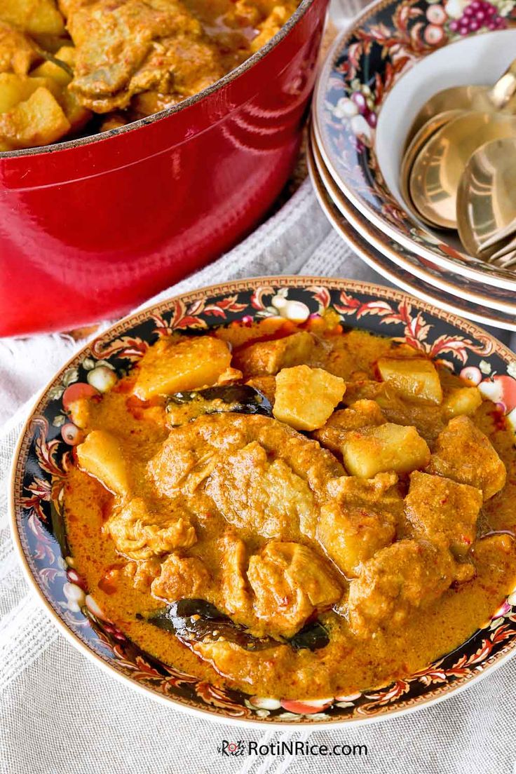 a bowl filled with curry and potatoes next to a red pot full of chicken stew