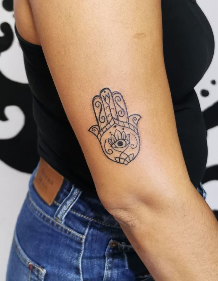 a woman's arm with a tattoo on it that has a hamsa hand