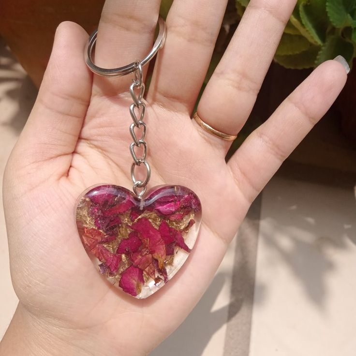 a hand holding a heart shaped keychain with dried flowers in the shape of a heart