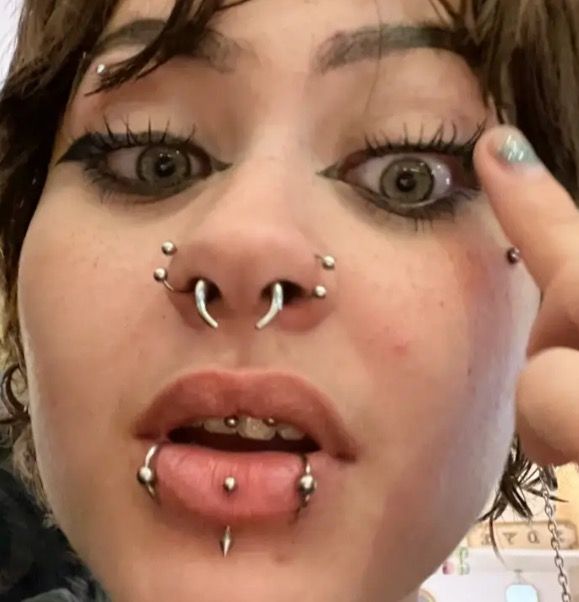 a close up of a person with piercings on her nose and nose ring in front of their face