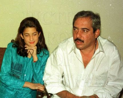 an old photo of a man and woman sitting on a couch looking at the camera