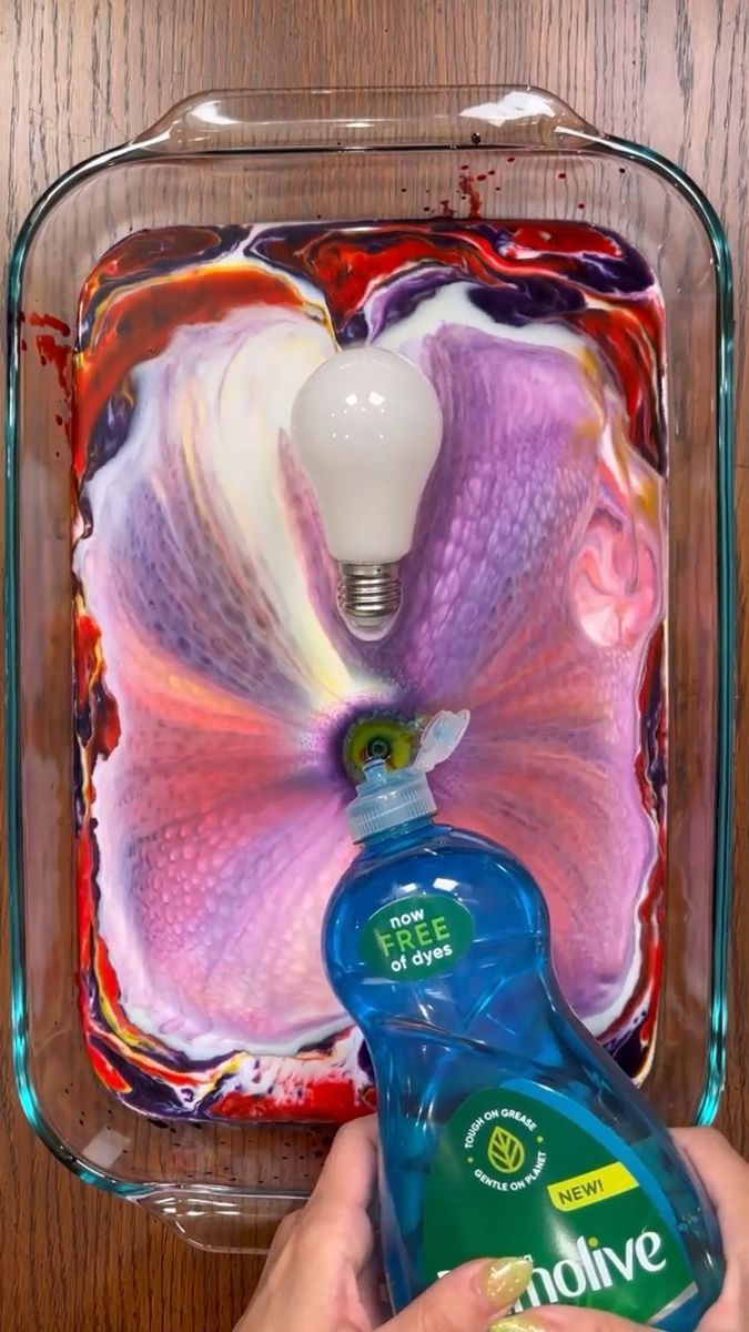 someone is holding a bottle of mouthwash in front of a flower and light bulb