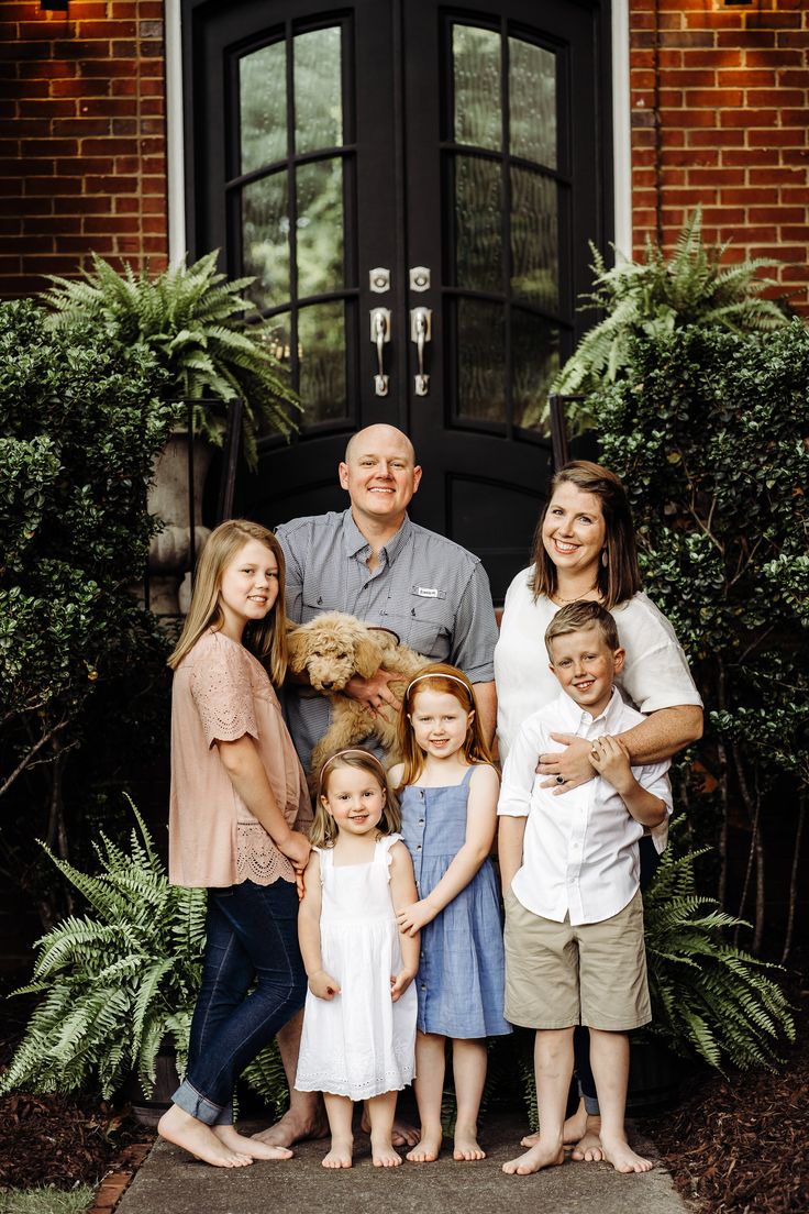 a family poses for a photo in front of their home