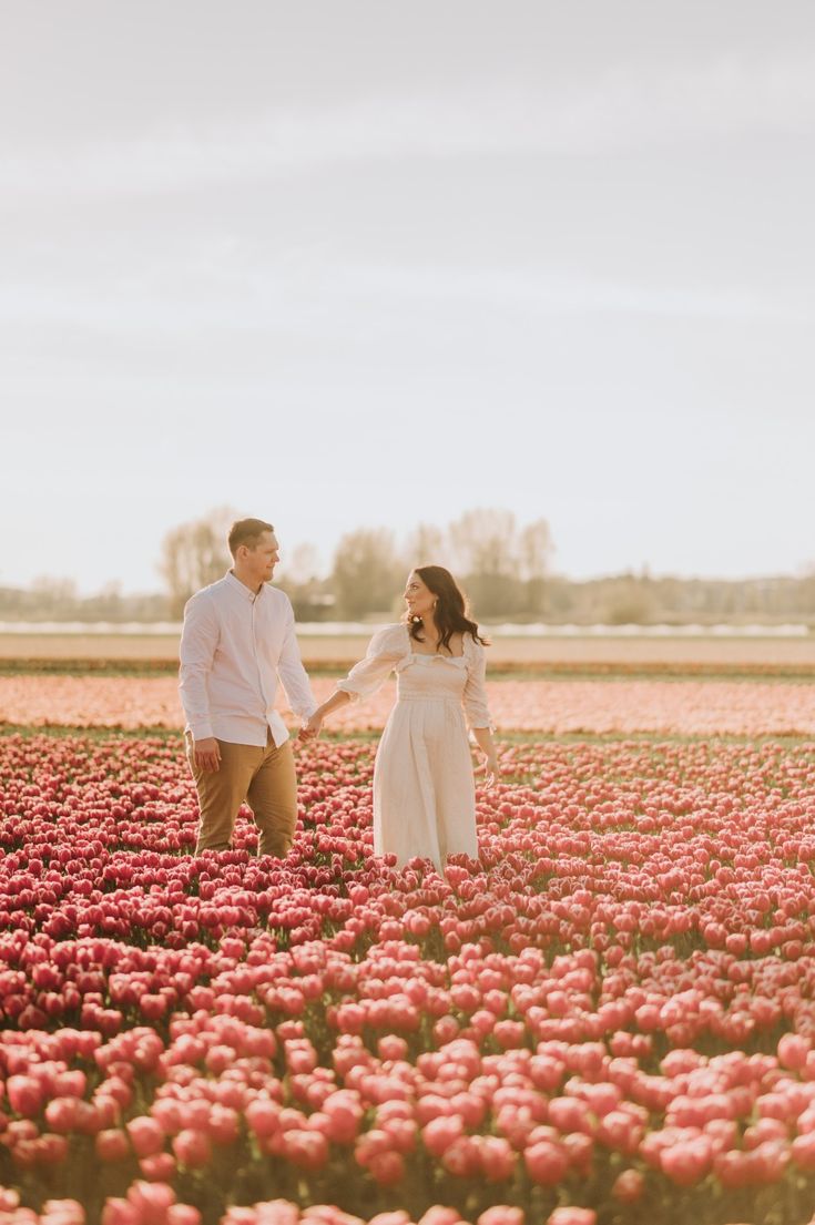 an engaged couple holding hands in a field of tulips