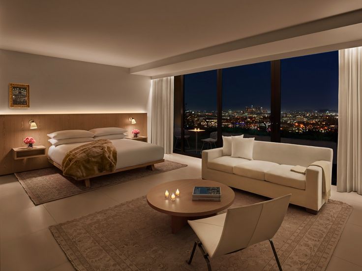 a bedroom with a large window and a view of the city at night from it's bed