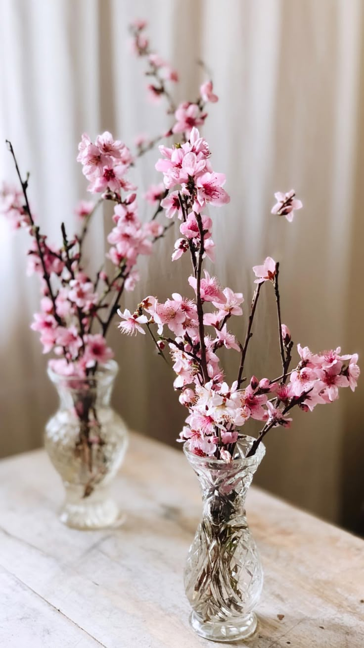 two vases filled with pink flowers on top of a table