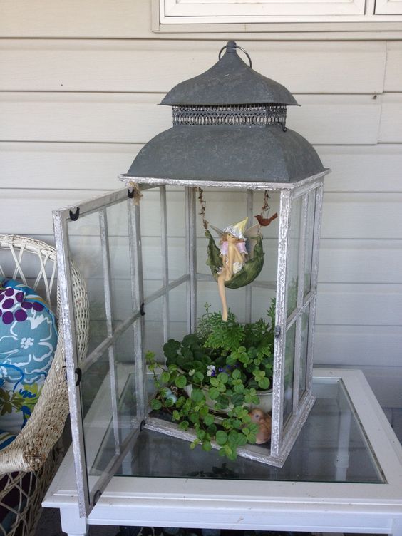 a white birdcage filled with plants on top of a table