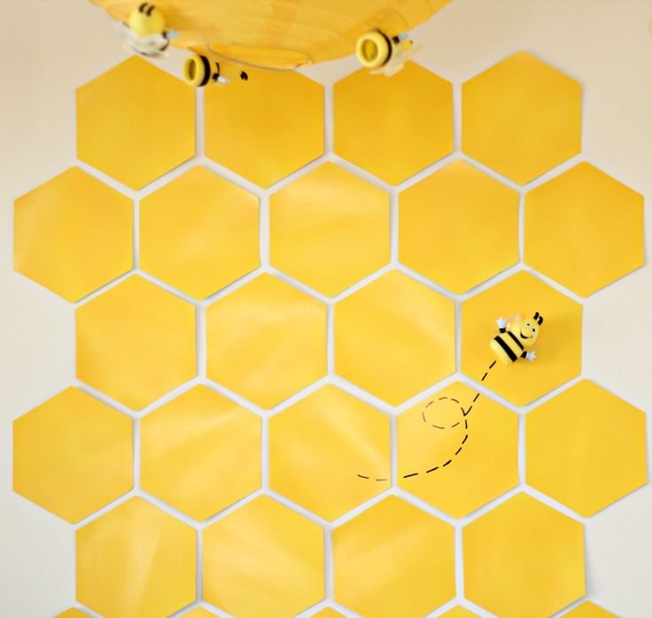 the bees are flying around the honeycombs on the wall in the room that is decorated with hexagonal tiles