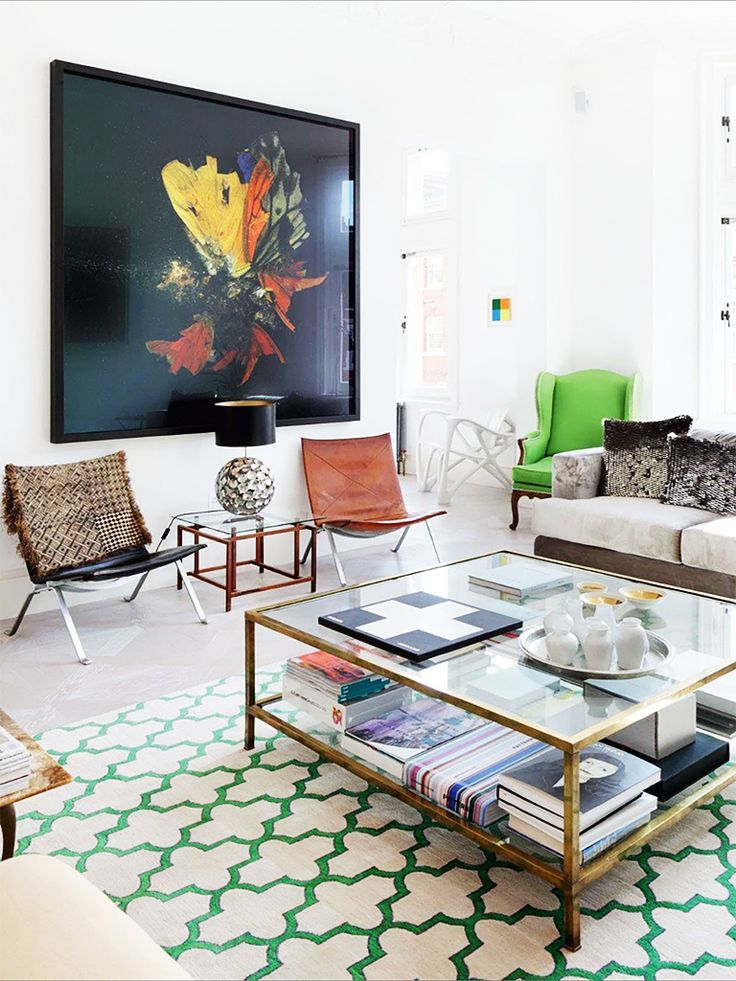 a living room filled with furniture and a large painting on the wall above it's coffee table