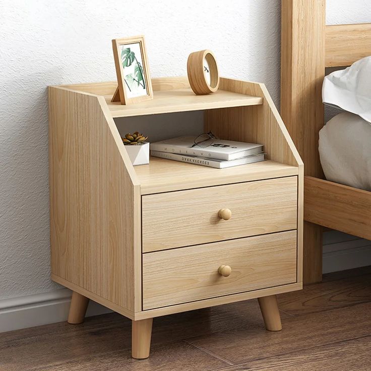 a nightstand with two drawers on top of it next to a bed and white sheets