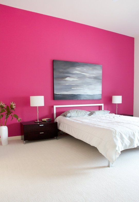 a bedroom painted in pink and white with a large painting on the wall above the bed