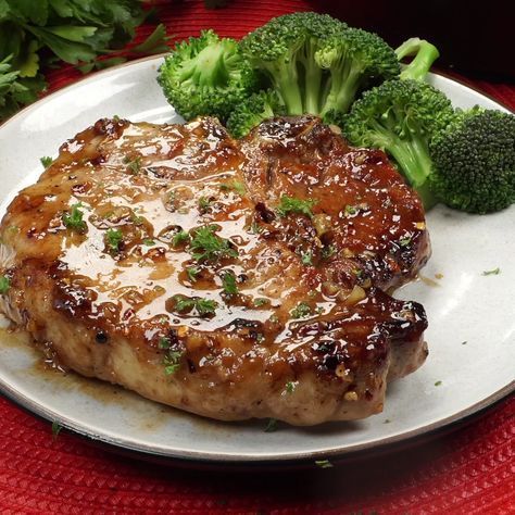 a white plate topped with meat and broccoli on top of a red table