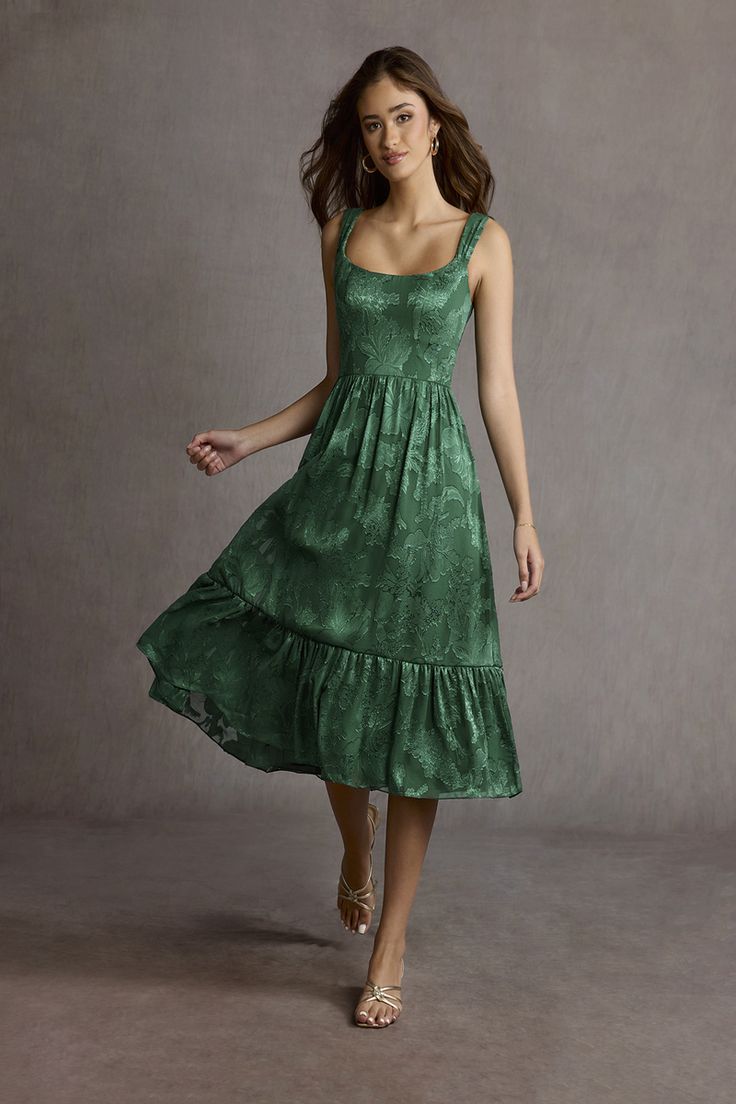 a woman in a green dress is posing for the camera with her hand on her hip