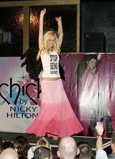 a woman in a pink skirt is on stage with her arms up and hands raised