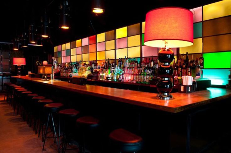 an empty bar with colorful lights and stools