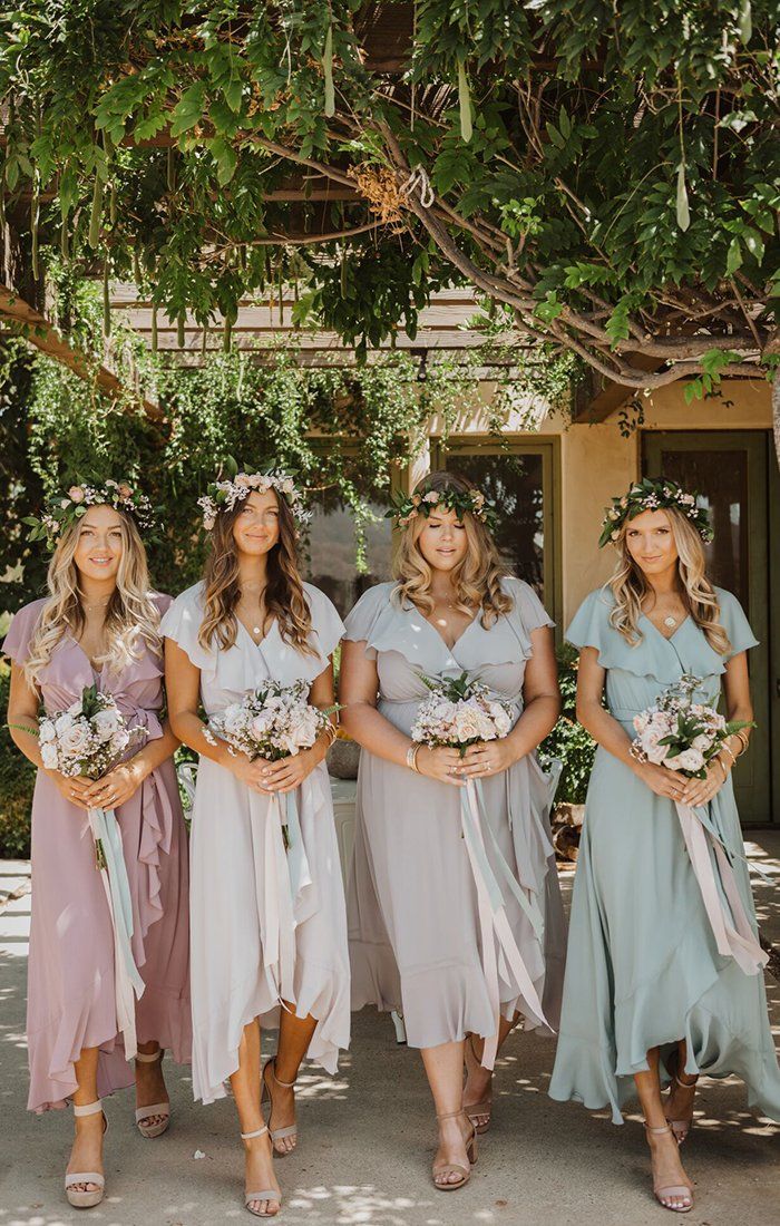 the bridesmaids are all dressed in pastel dresses and flower crowns for their wedding