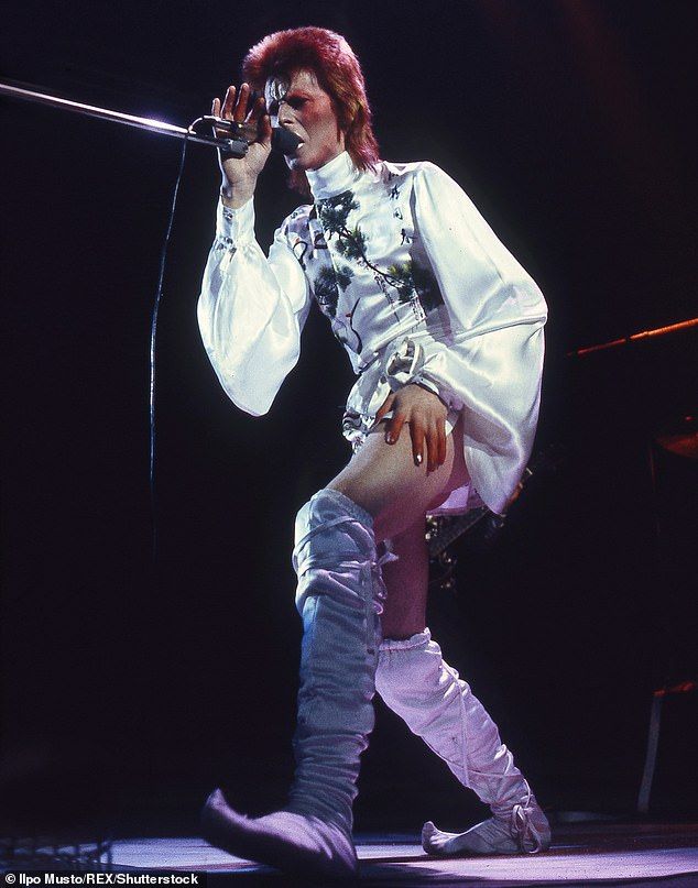 the man is dressed in all white and holding a microphone