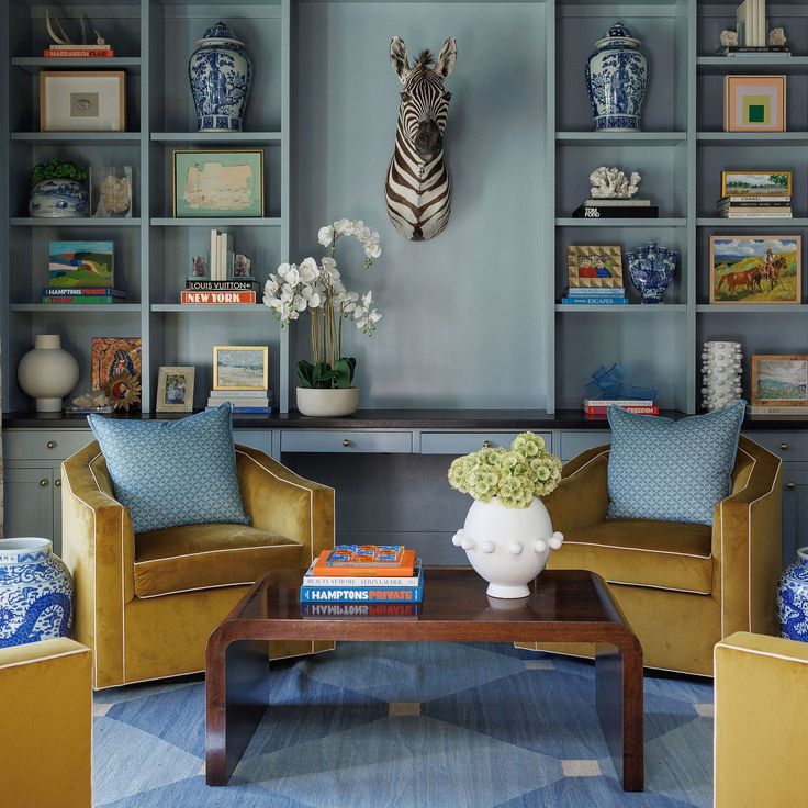 a living room with two chairs and a coffee table in front of a bookshelf