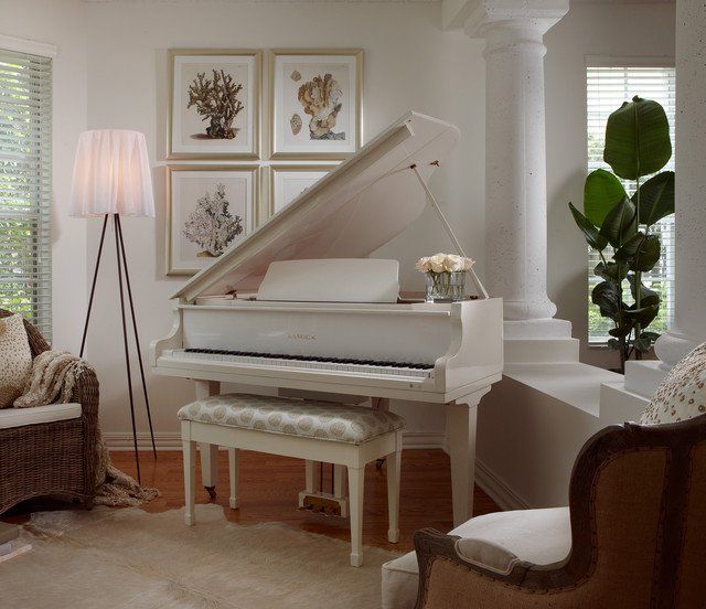 a white piano in a living room next to a couch