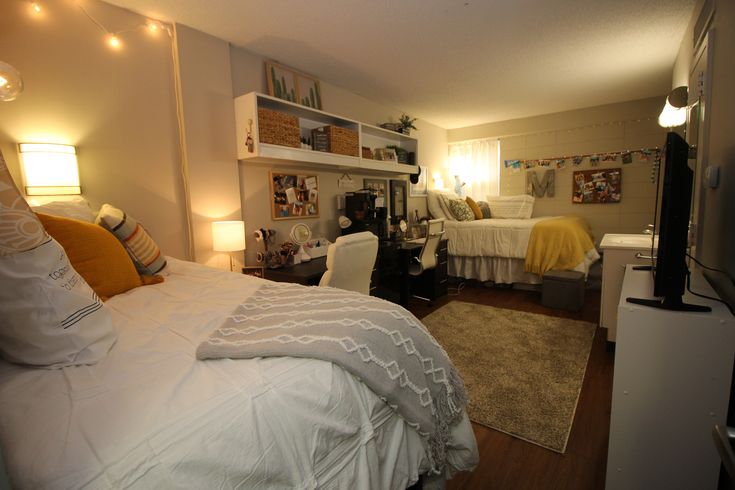 a bed room with a neatly made bed next to a tv on a stand and two lamps