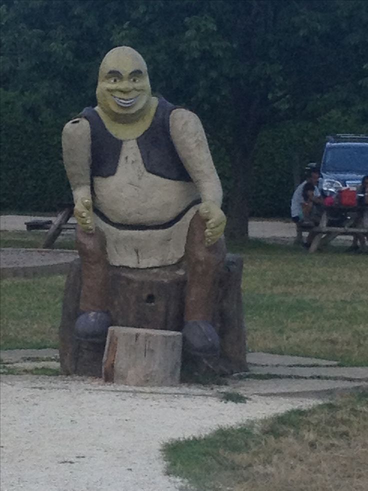 a large statue of a man sitting on top of a tree stump in a park