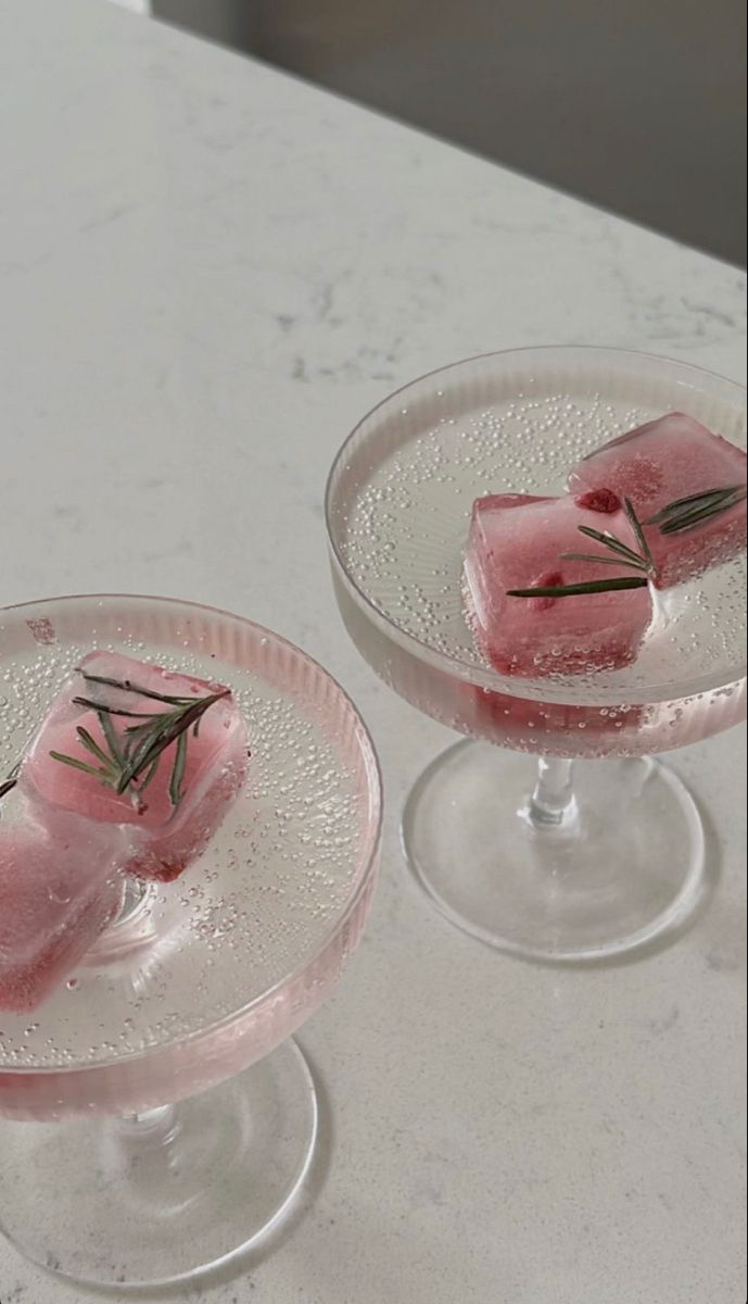 two small desserts sitting on top of each other in glass dishes with pink icing and sprinkles