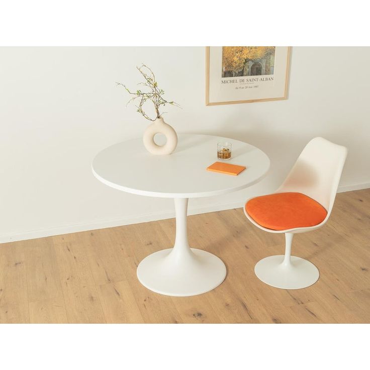 a white table with an orange chair next to it