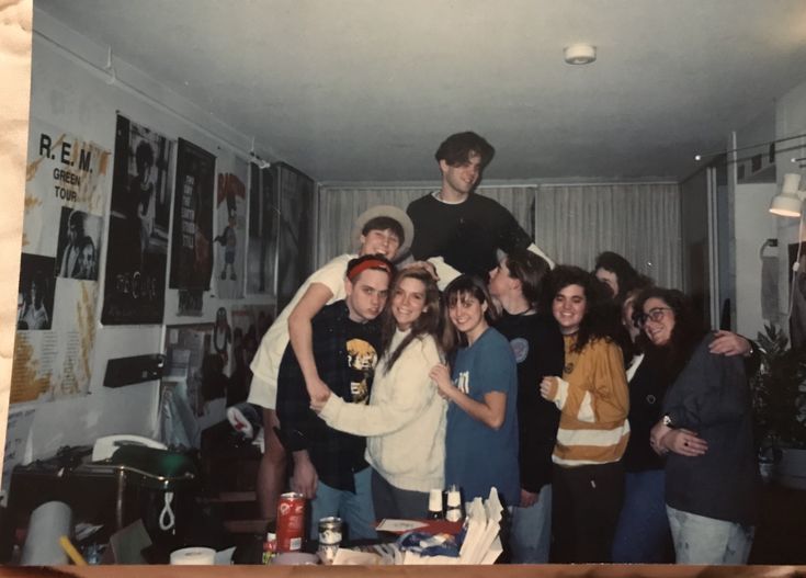 a group of people posing for a photo in a room with pictures on the wall