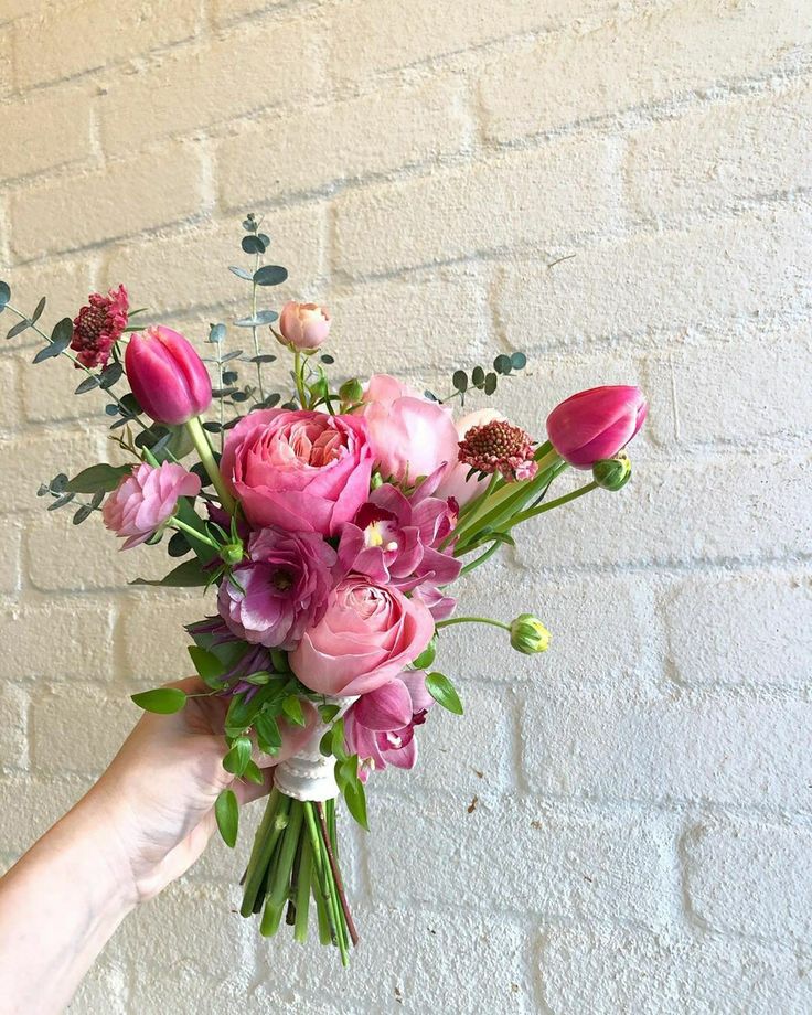 a person holding a bouquet of flowers in front of a brick wall