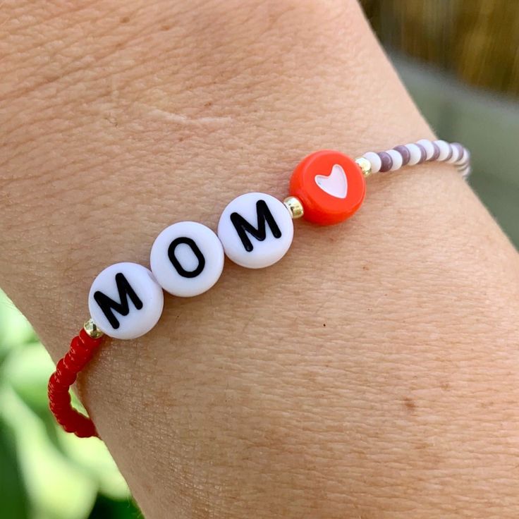 multi colored and patterned seed bead bracelet with MOM, gold beads and a heart bead strung on elastic please gently roll on and off to prolong its life handmade in venice, ca Handmade White Friendship Bracelets For Mother's Day, Handmade White Beaded Bracelets For Mother's Day, Everyday White Beaded Bracelets With Heart Beads, Red Beaded Bracelets For Mother's Day, Heart Beaded Bracelets For Mother's Day, Heart-shaped Letter Beaded Bracelets For Mother's Day, White Round Beads Friendship Bracelets For Mother's Day, Mother's Day Beaded Bracelets With Heart Beads, Everyday White Heart Bracelet With Letter Beads