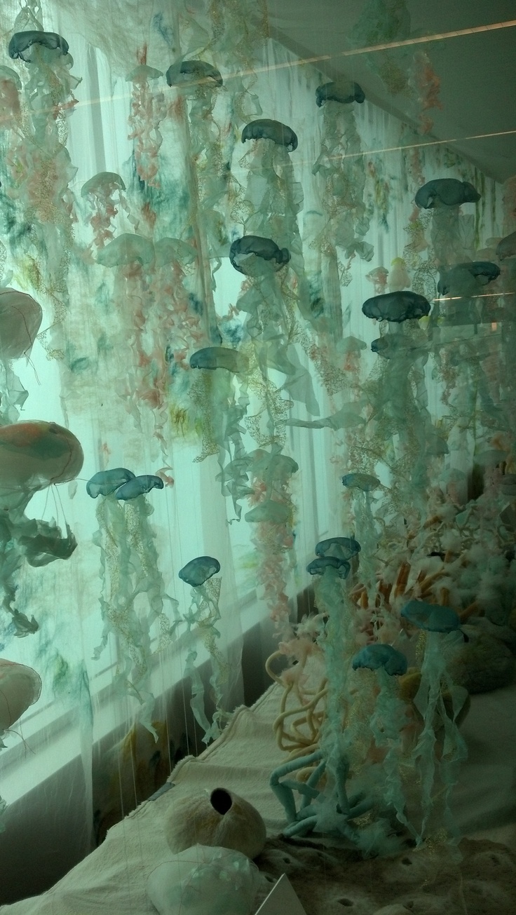 a room filled with lots of jellyfish hanging from the ceiling next to a window