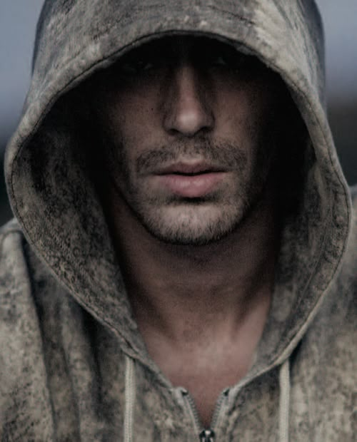 a man wearing a hoodie looking at the camera with a serious look on his face