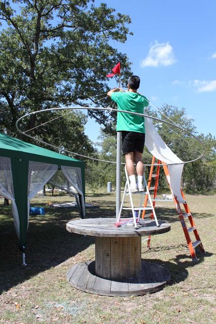 a man standing on top of a wooden platform next to a green and white tent