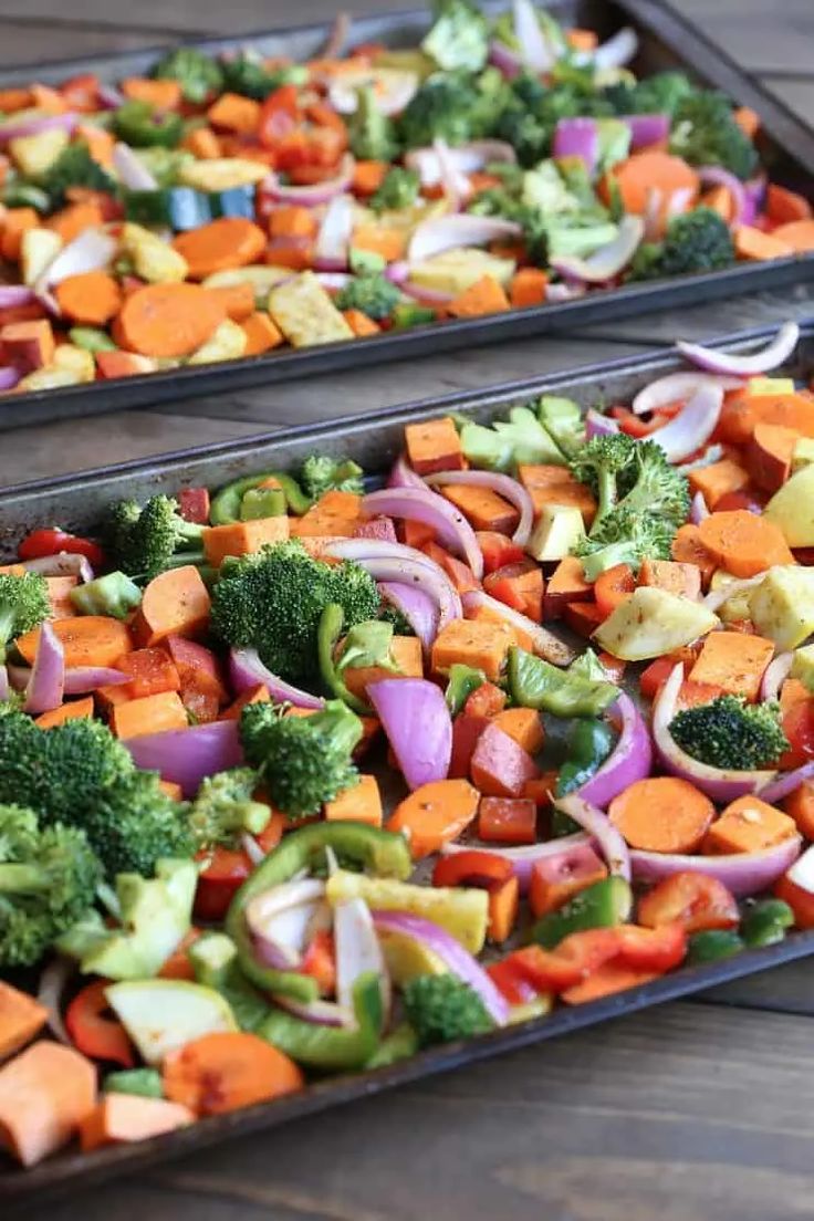 two trays filled with vegetables sitting on top of a wooden table next to each other