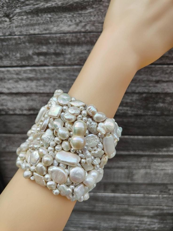 a woman's arm with a bracelet made out of shells and pearls on it