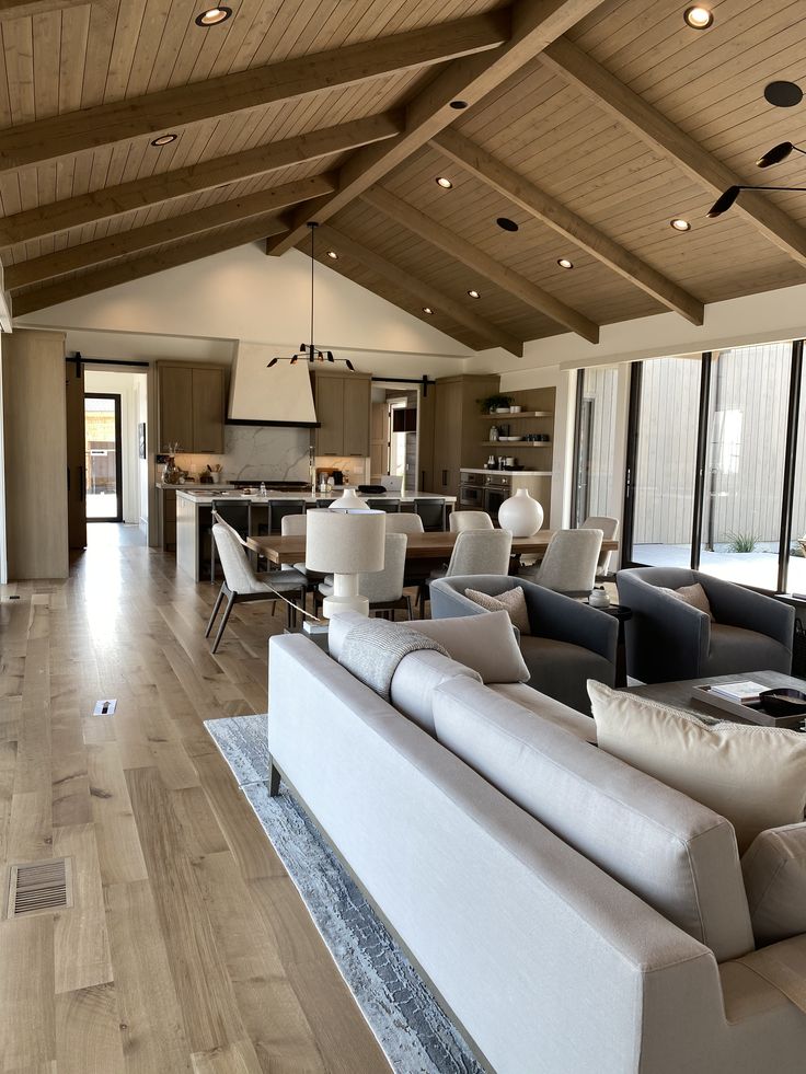 a living room filled with lots of furniture and large open space kitchen in the background